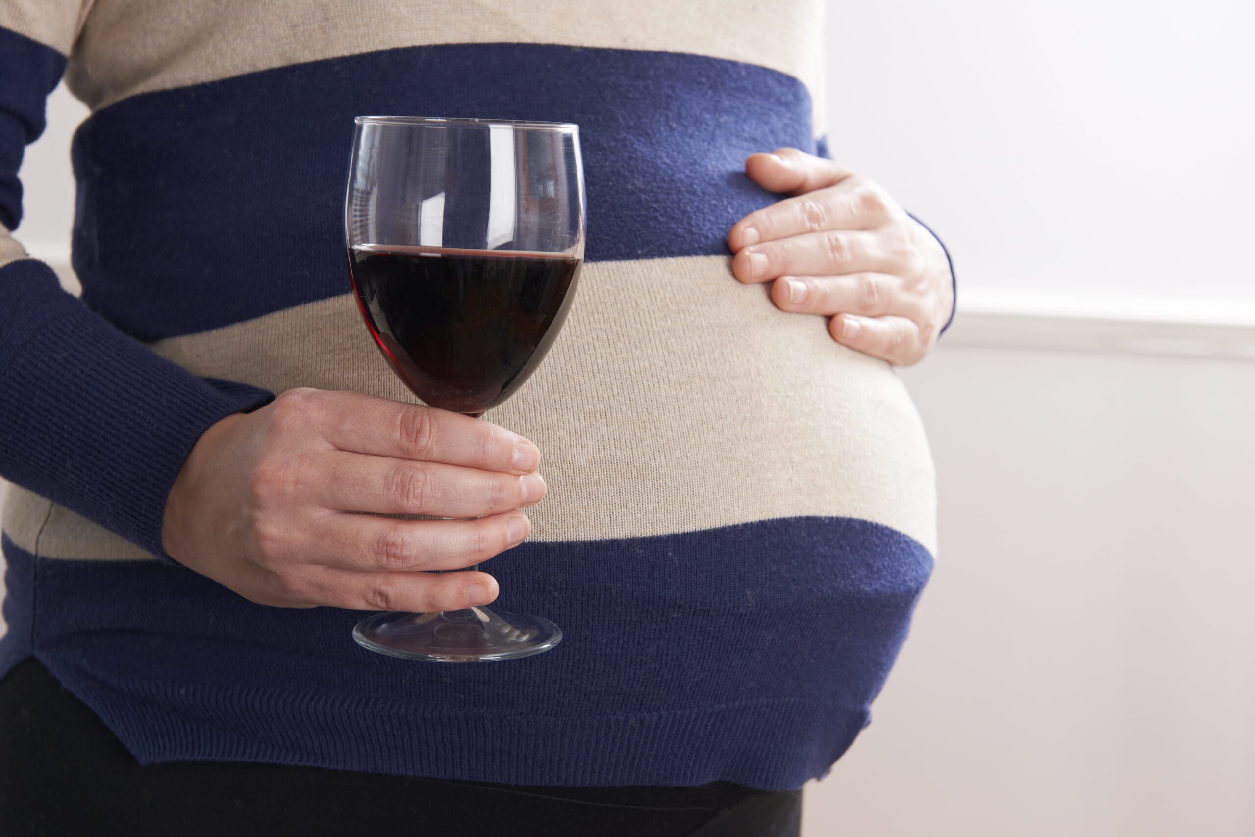 pregnant woman drinking a glass of wine